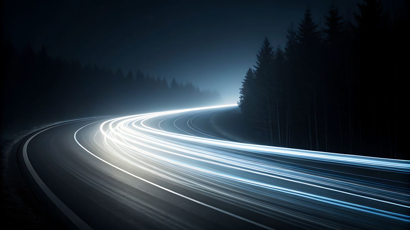 Long-exposure light trails on a forest road at night
